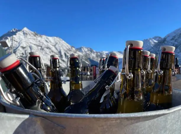 Apres-ski bier in emmer met bergen op achtergrond.